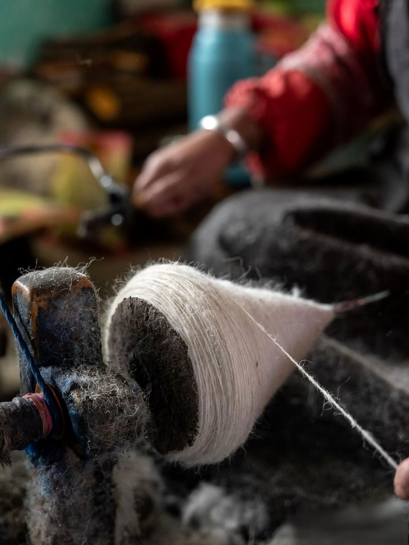 Hand-spun wool thread wound on a wooden spindle, close-up of the fine white fiber